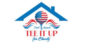 The image is a logo for the "First Annual Tee It Up for Charity" golf tournament. It includes a golf ball designed with an American flag pattern on a golf tee, surrounded by decorative red and blue wave elements, beneath a stylized blue roof symbolizing shelter or home. The logo uses patriotic red, white, and blue colors to emphasize the charitable and community-oriented nature of the event.