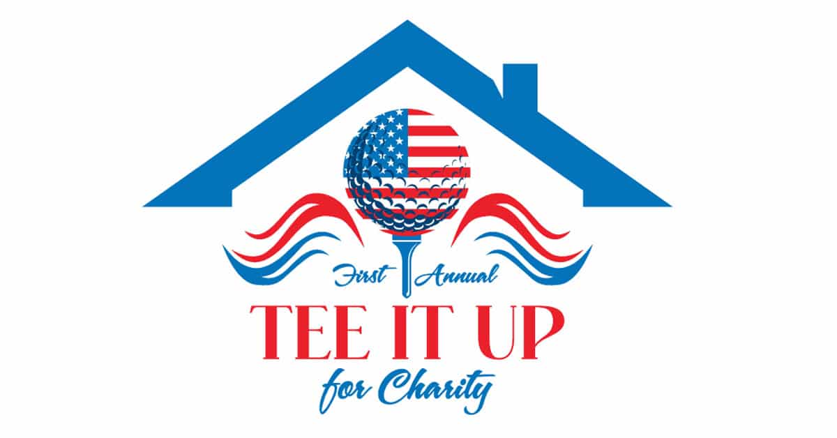 The image is a logo for the "First Annual Tee It Up for Charity" golf tournament. It includes a golf ball designed with an American flag pattern on a golf tee, surrounded by decorative red and blue wave elements, beneath a stylized blue roof symbolizing shelter or home. The logo uses patriotic red, white, and blue colors to emphasize the charitable and community-oriented nature of the event.